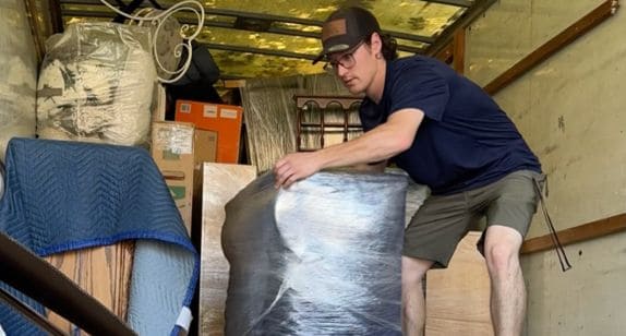 Professional mover handling large item in storage unit.