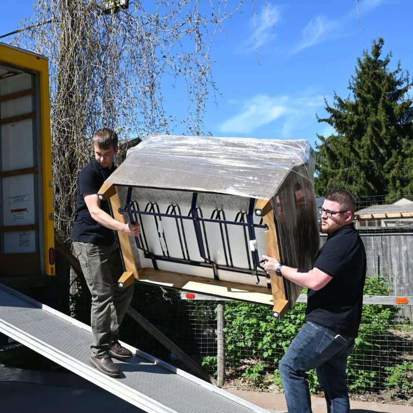 Two movers lifting a large piece of furniture onto a truck.