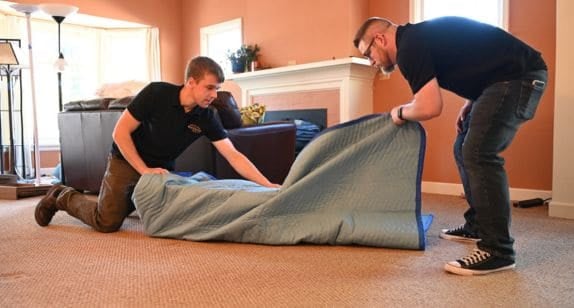 Professional movers wrapping furniture for safe transport.