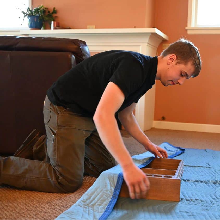 Man packing a wooden box for moving in a home setting.