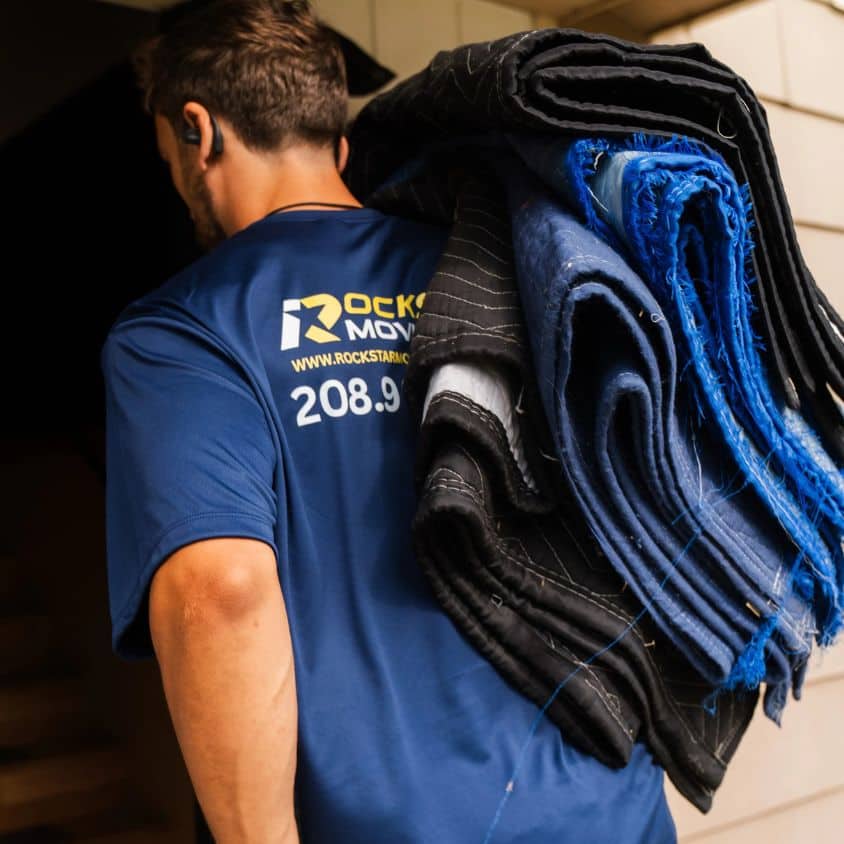 Moving worker carrying blankets for safe furniture transport.