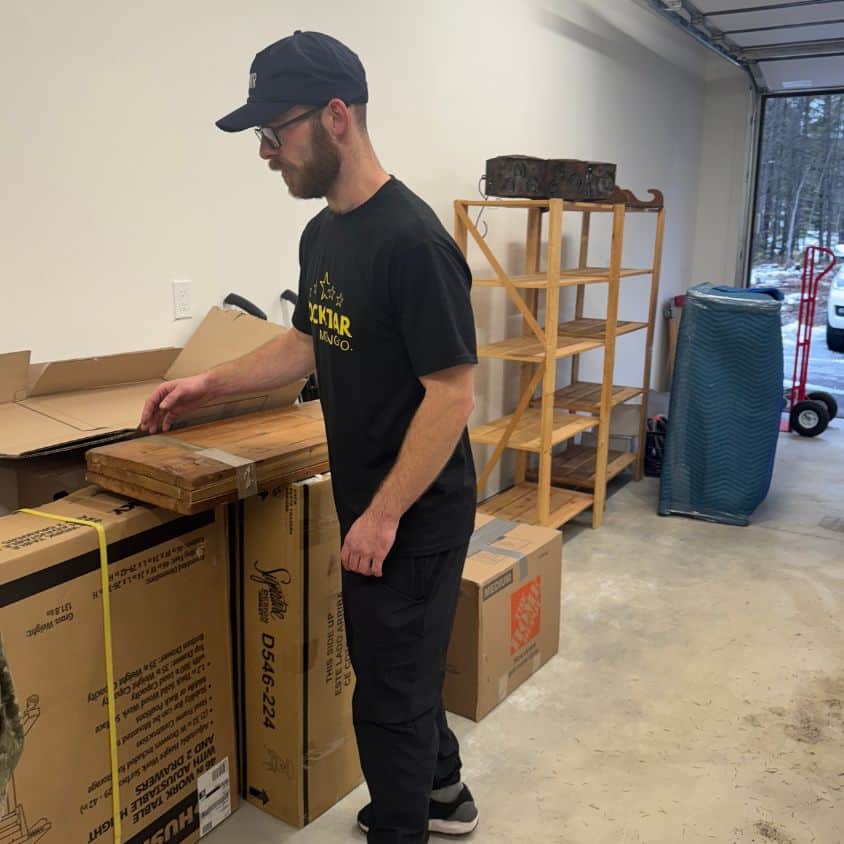 Moving company worker packing boxes in a garage or storage area.